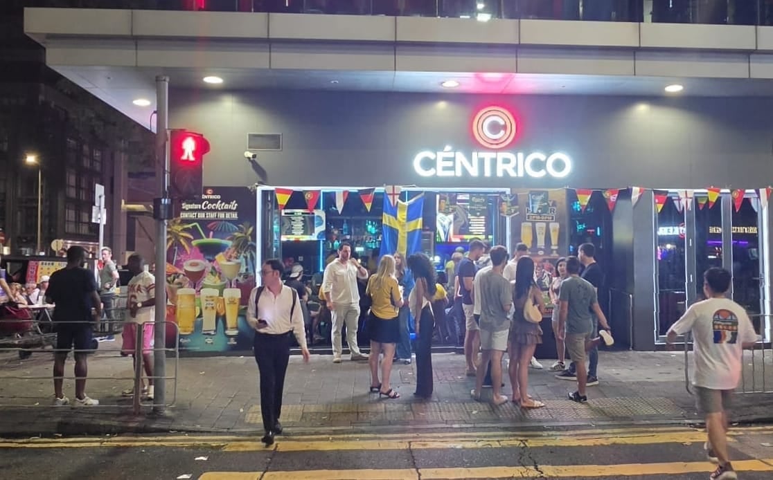 Centrico storefront at night with neon signage and customers walking outside on a city street